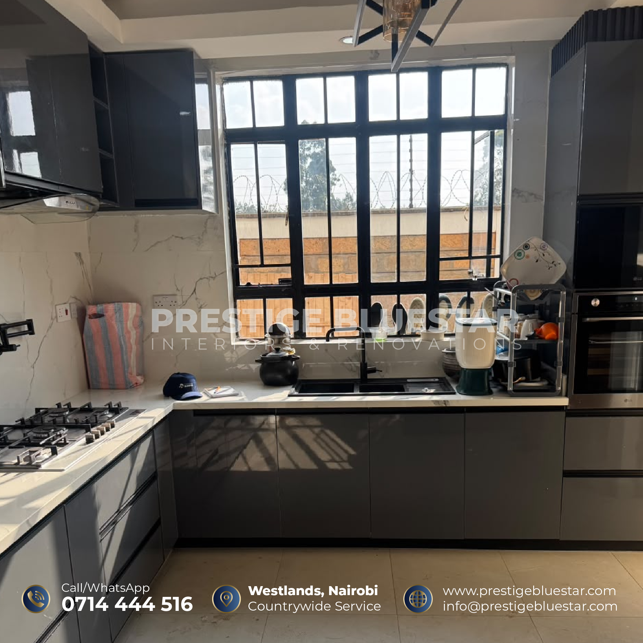 A completed modern kitchen featuring premium grey and white custom cabinets, marble countertops, a pull-out pantry, stylish backsplash, and integrated storage accessories.